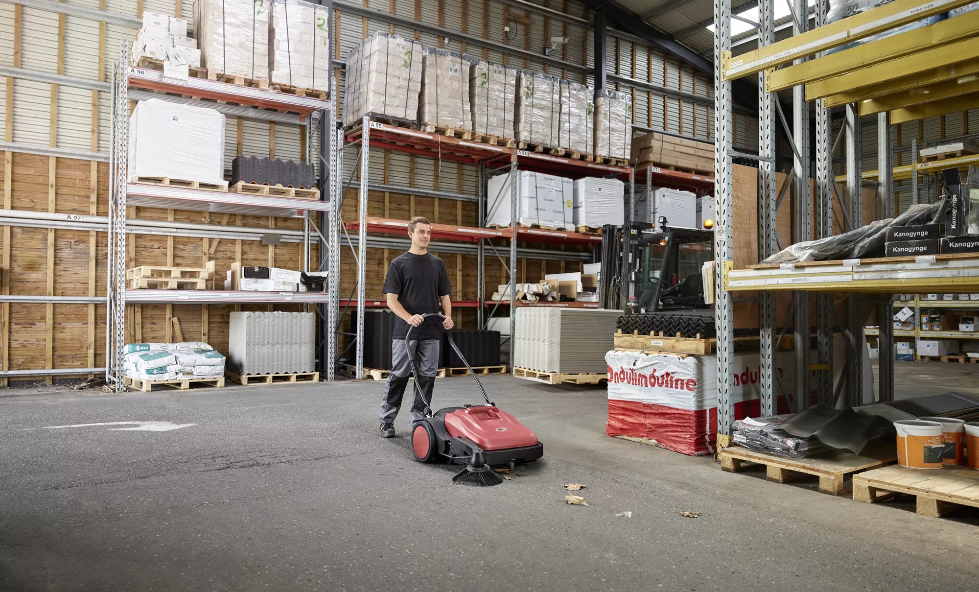 Man operating a Viper manual sweeper in a warehouse. This is the Viper 28" Manual Push Sweeper, w/Right Side Broom, 10 Gallon Hopper