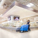 Operator pushing the Clarke BOOST 23 Orbital floor scrubber in a grocery store.